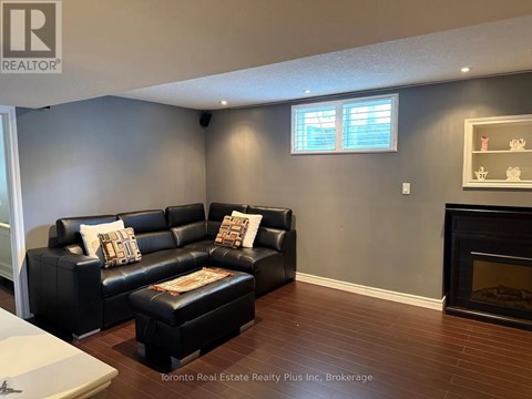 A living room with a black leather couch and ottoman.