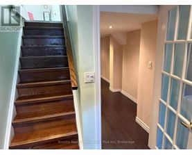A hallway with a staircase and a door with a glass panel.