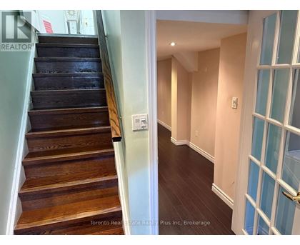 A hallway with a staircase and a door with a glass panel.
