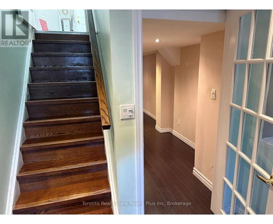 A hallway with a staircase and a door with a glass panel.