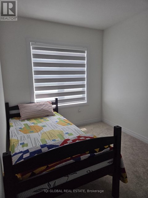 A bedroom with a bed and a window with blinds.