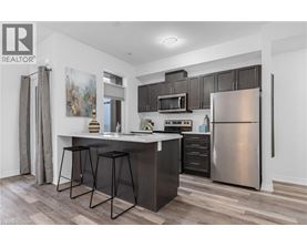 A modern kitchen with a bar stool and a refrigerator.
