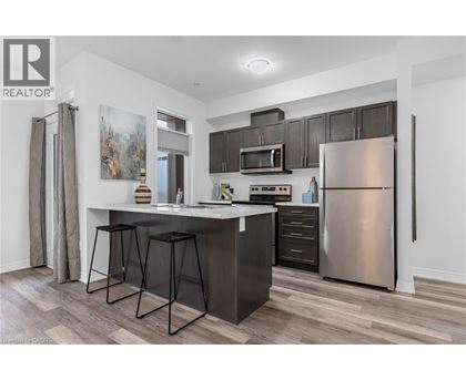 A modern kitchen with a bar stool and a refrigerator.
