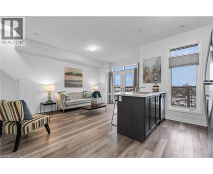 A well-lit, spacious living room with a striped armchair and a kitchen area with a refrigerator and sink.