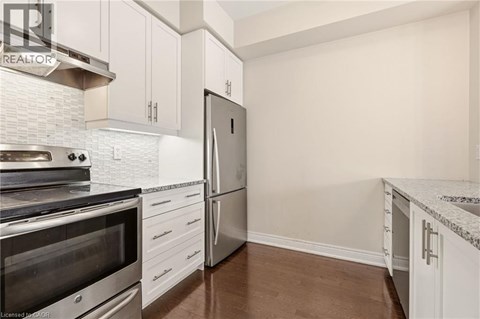 A kitchen with white cabinets and a stainless steel refrigerator.
