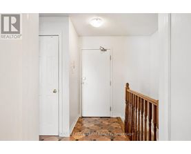 A white door with a gold handle is in a white room.