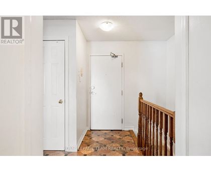 A white door with a gold handle is in a white room.