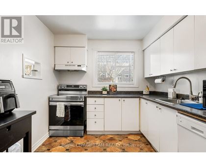 A kitchen with white cabinets and a black countertop.