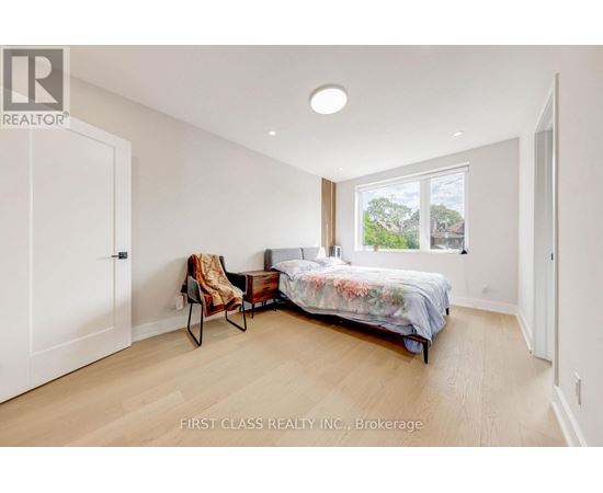 A bedroom with a bed, chair, and window.