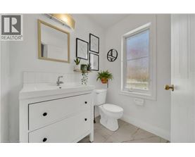 A white bathroom with a sink, toilet, and a window.