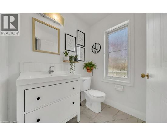 A white bathroom with a sink, toilet, and a window.