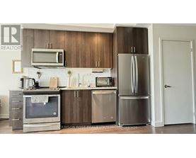 A kitchen with a refrigerator, oven, and microwave.