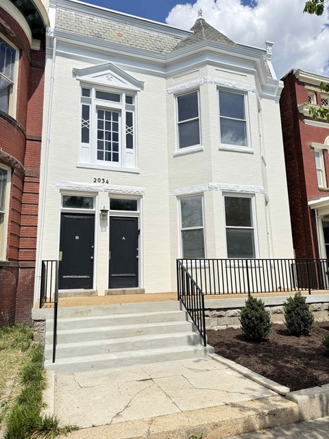 A white two story house with black doors and windows.