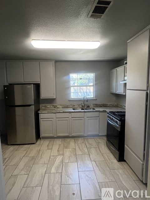 A kitchen with a refrigerator, sink, and oven.
