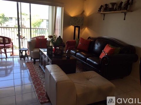 A living room with a black couch and a white chair.