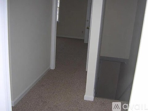 A hallway with a carpeted floor and white walls.