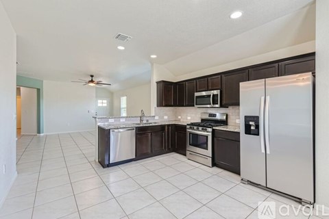 A kitchen with white tiled floors and a stainless steel refrigerator.