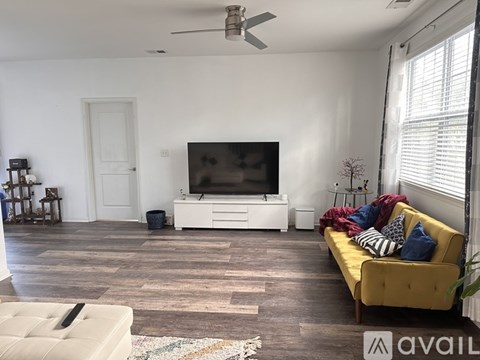 A living room with a yellow couch and a white entertainment center.