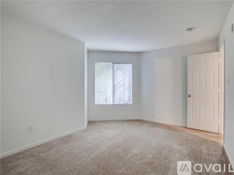 A spacious room with a carpeted floor and a window letting in natural light.