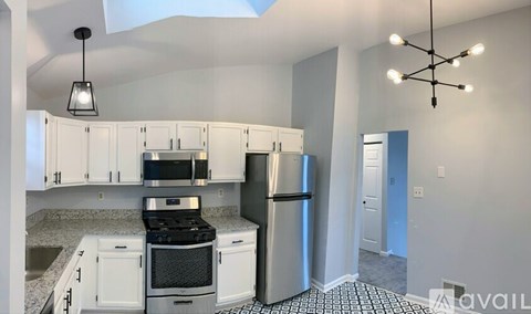 A kitchen with white cabinets and a black and white checkered floor.