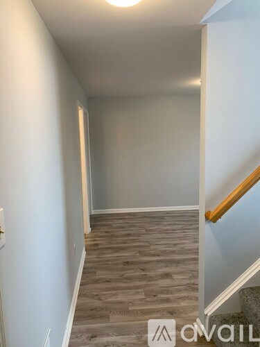 A hallway with wooden flooring and a staircase.