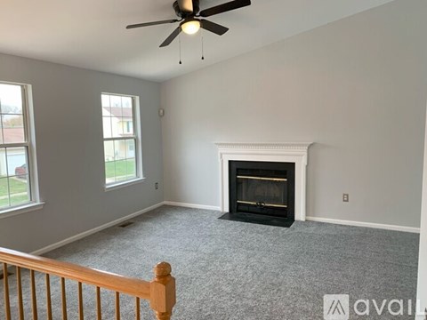 A living room with a fireplace and a ceiling fan.