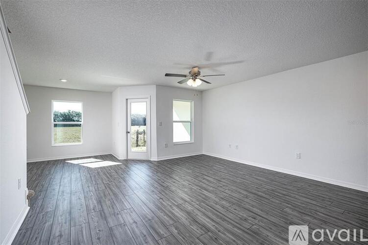 A spacious room with wood flooring and a ceiling fan.
