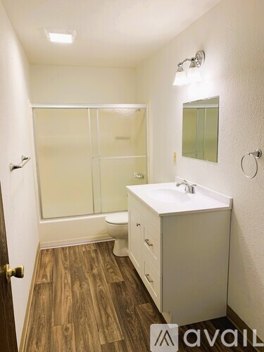 A bathroom with a white sink and a wooden floor.