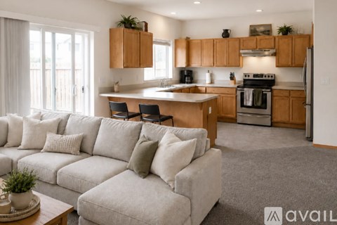 A modern living room with a grey couch and a kitchen in the background.