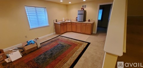 A living room with a rug and a kitchen area in the background.