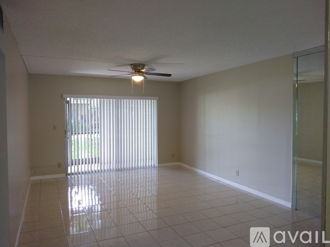 A spacious room with a ceiling fan and a sliding glass door.