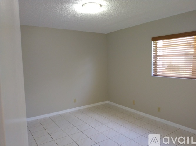 A room with a window covered by blinds and a tiled floor.
