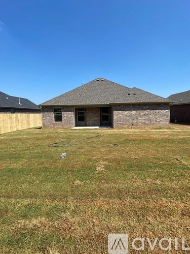 A house with a grey roof and a brown door is surrounded by a grassy field.