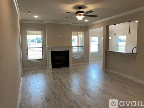 A spacious living room with a fireplace and a ceiling fan.