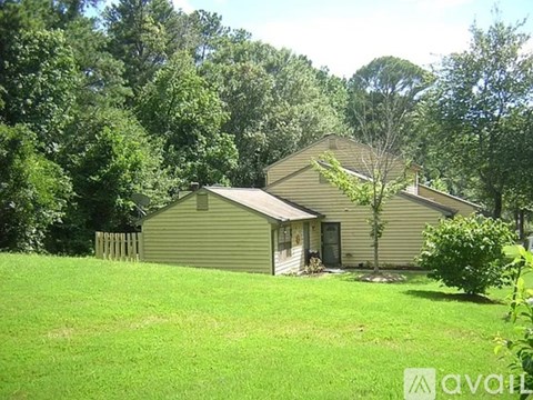 A house with a green lawn and trees in the background.