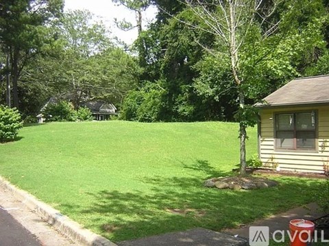 A house with a green lawn and trees in the background.