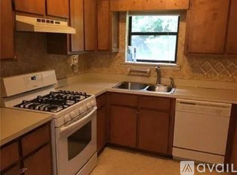 A kitchen with a white stove and wooden cabinets.