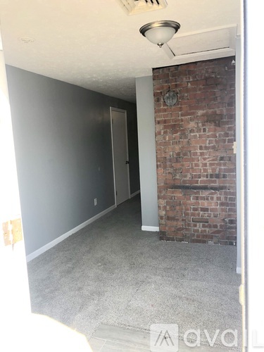 A room with a brick wall and a ceiling fan.