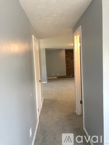 A hallway with a carpeted floor and white walls.