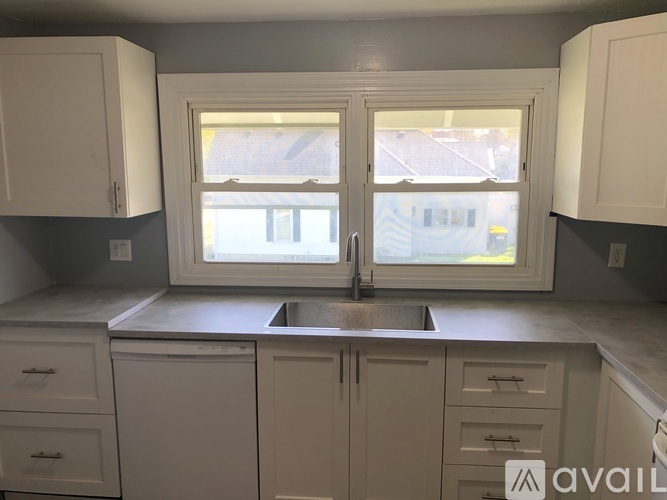 A kitchen with white cabinets and a window.