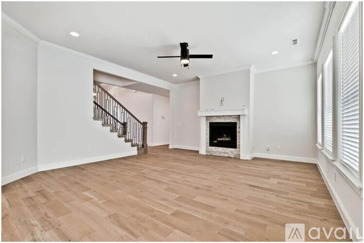 A spacious room with a fireplace and a staircase.