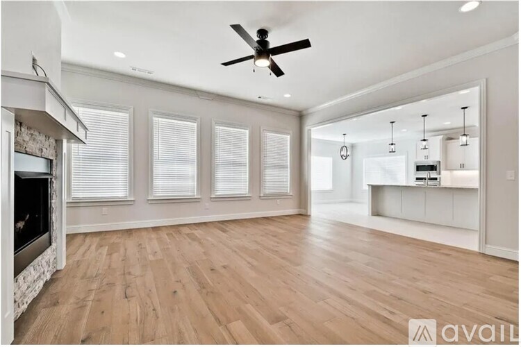 A spacious living room with a fireplace and a ceiling fan.