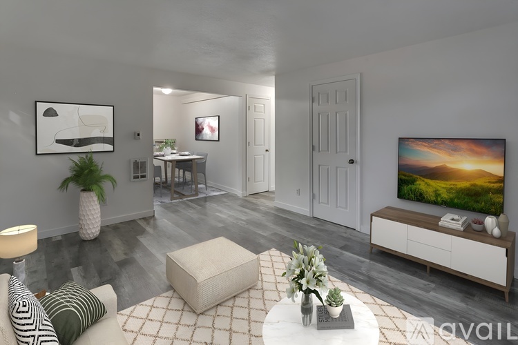A living room with a white couch, a coffee table, and a television on the wall.