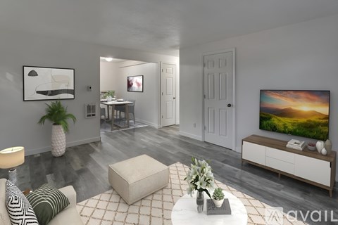 A living room with a white couch, a coffee table, and a television on the wall.