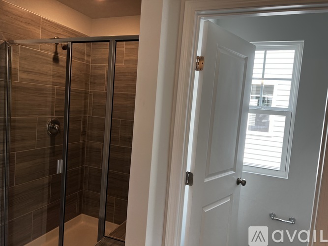 A bathroom with a glass shower stall and a white door.