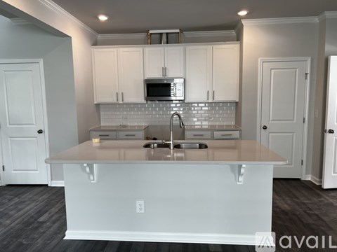 A kitchen with white cabinets and a grey floor.