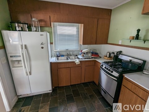 A kitchen with a white refrigerator, stove, and wooden cabinets.
