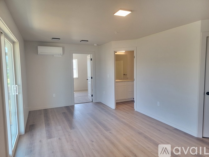 A spacious room with wooden flooring and white walls.