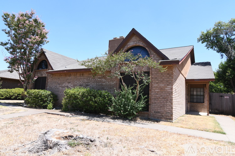 A house with a brown roof and a tree in front of it.