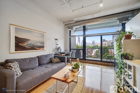 A living room with a grey couch and a painting on the wall.